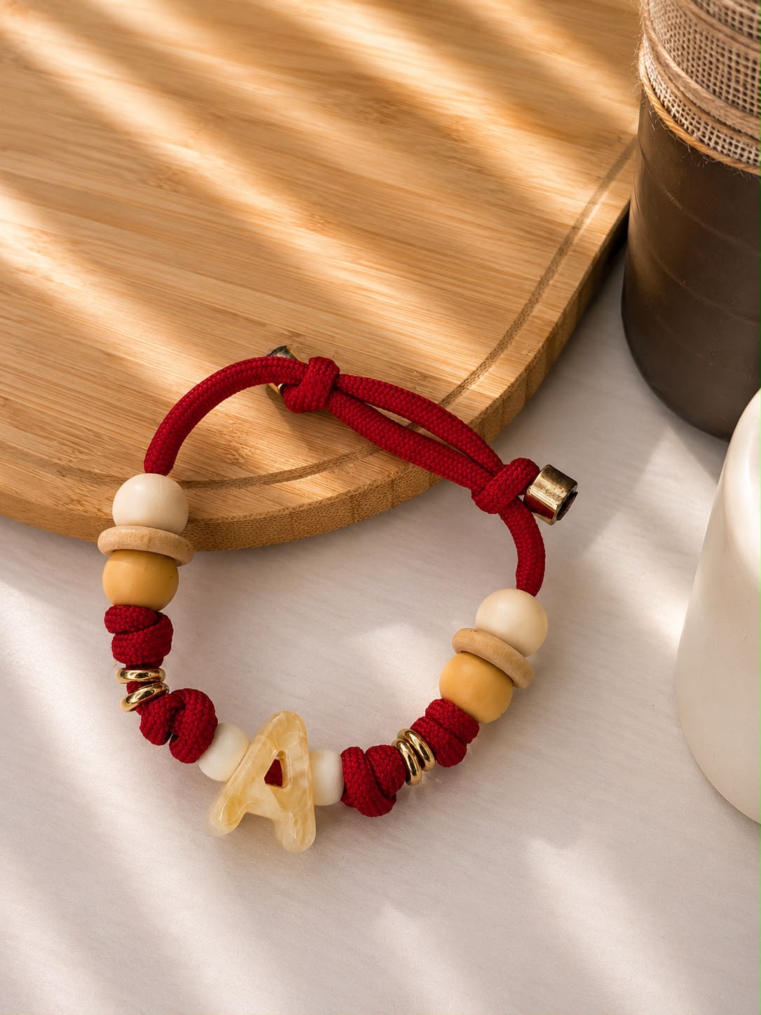 Collanina Essential rossa con iniziale A, nodi e perle decorative.