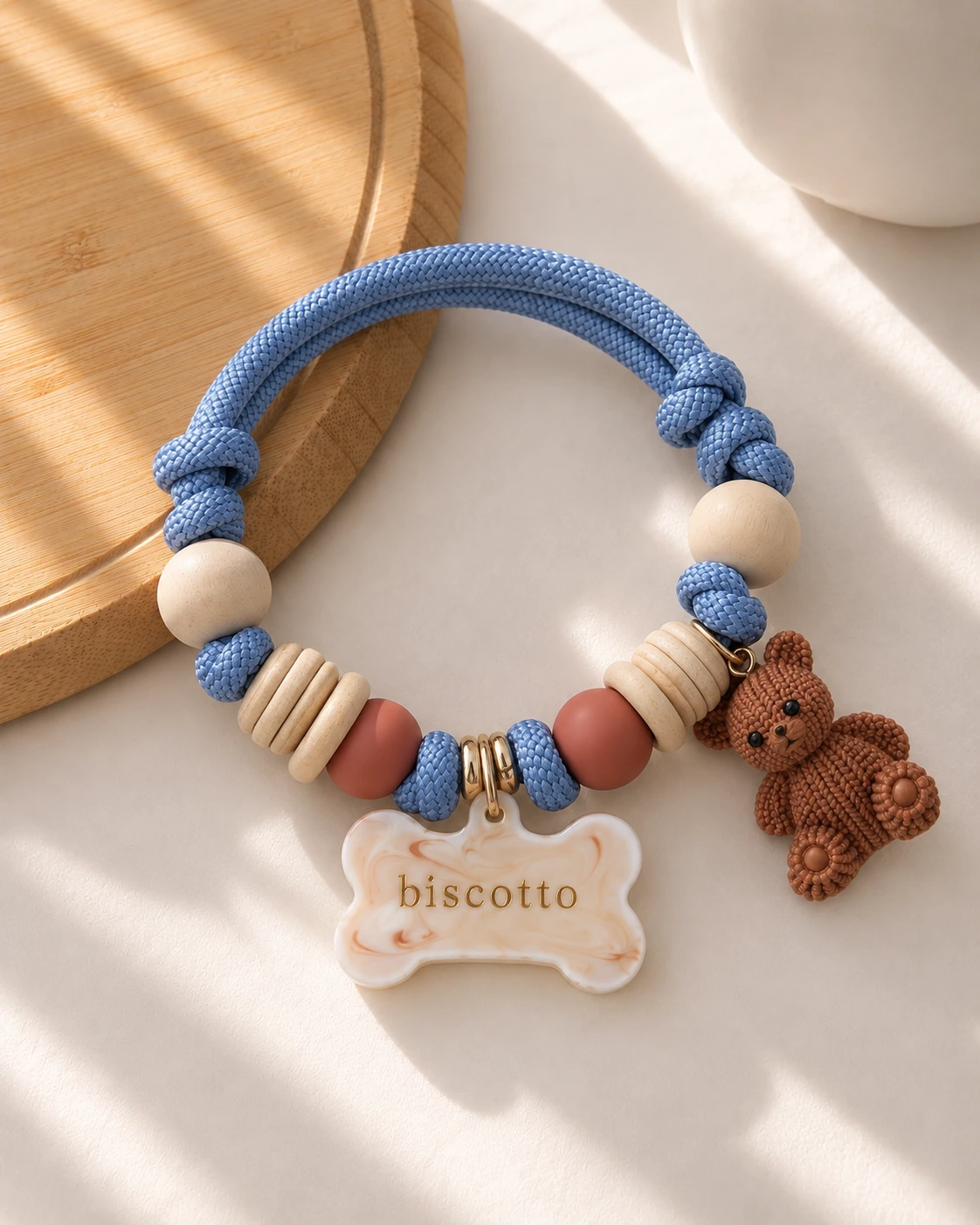 Collanina Prestige con cordino blu, perline chiare, ciondolo orsetto e targhetta in resina con nome biscotto.